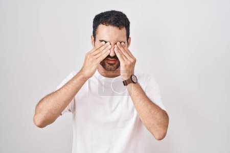 Téléchargez les photos : Bel homme hispanique debout sur fond blanc frottant les yeux pour la fatigue et les maux de tête, somnolent et l'expression fatiguée. problème de vision - en image libre de droit