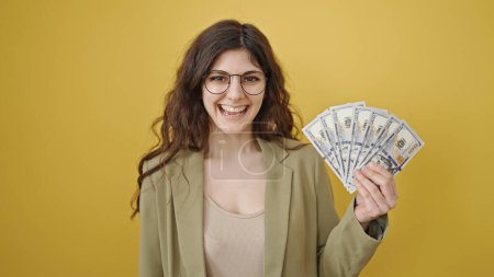 Photo for Young beautiful hispanic woman smiling confident holding dollars over isolated yellow background - Royalty Free Image