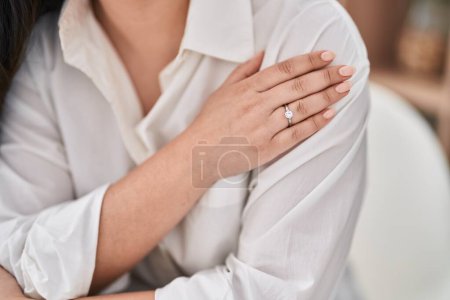 Foto de Mujer hispana joven con anillo de compromiso sentado en la mesa en casa - Imagen libre de derechos