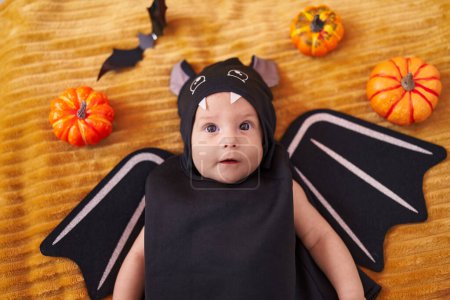 Téléchargez les photos : Adorable bébé caucasien portant un costume de chauve-souris couché sur le canapé à la maison - en image libre de droit