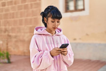 Téléchargez les photos : Jeune femme utilisant un smartphone dans la rue - en image libre de droit