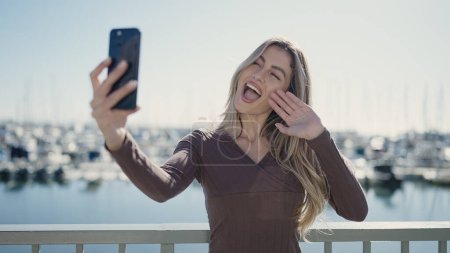 Photo for Young blonde woman smiling confident having video call at seaside - Royalty Free Image