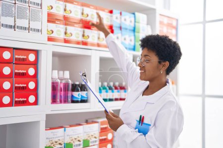 Téléchargez les photos : Une pharmacienne afro-américaine lisant un document de travail à la pharmacie - en image libre de droit