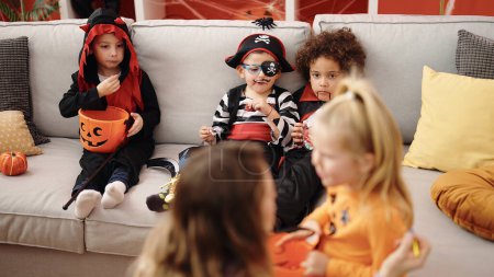 Foto de Grupo de niños comiendo caramelos que tienen maquillaje de Halloween en casa - Imagen libre de derechos