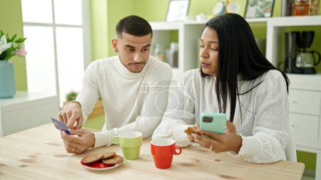 Foto de Hombre y mujer pareja desayunando de compras con smartphone y tarjeta de crédito en casa - Imagen libre de derechos