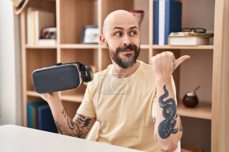 Photo for Young hispanic man wearing virtual reality glasses pointing thumb up to the side smiling happy with open mouth - Royalty Free Image