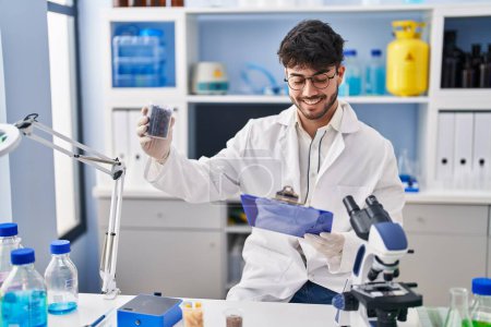 Téléchargez les photos : Young hispanic man scientist weighing sample reading document at laboratory - en image libre de droit