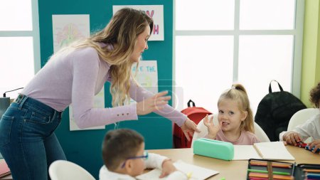 Photo for Woman with boy and girl having lesson sitting on table at classroom - Royalty Free Image