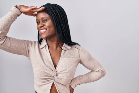 Photo for African woman with braids standing over white background very happy and smiling looking far away with hand over head. searching concept. - Royalty Free Image