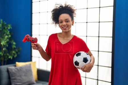 Foto de Joven mujer afroamericana jugando fútbol videojuego guiño mirando a la cámara con expresión sexy, cara alegre y feliz. - Imagen libre de derechos