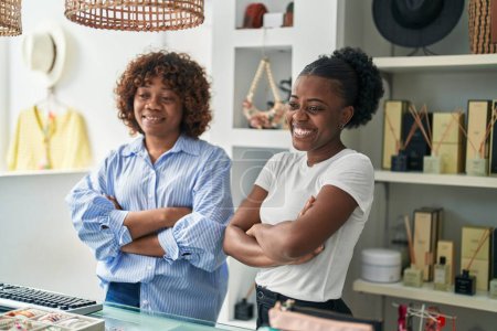 Téléchargez les photos : Femmes afro-américaines vendeuses debout avec les bras croisés geste au magasin de vêtements - en image libre de droit
