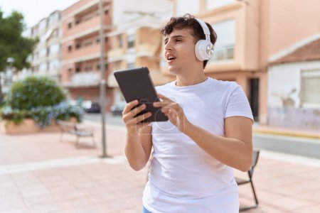Photo for Non binary man using touchpad and headphones at street - Royalty Free Image