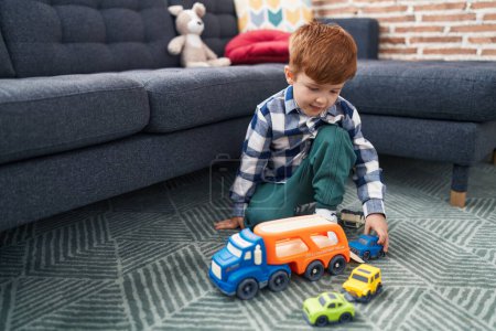 Foto de Adorable niño jugando con el juguete del coche sentado en el suelo en casa - Imagen libre de derechos