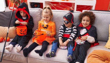 Téléchargez les photos : Groupe d'enfants portant un costume d'Halloween assis sur le canapé à la maison - en image libre de droit