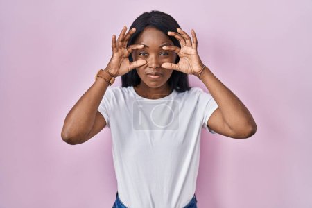 Photo for African young woman wearing casual white t shirt trying to open eyes with fingers, sleepy and tired for morning fatigue - Royalty Free Image