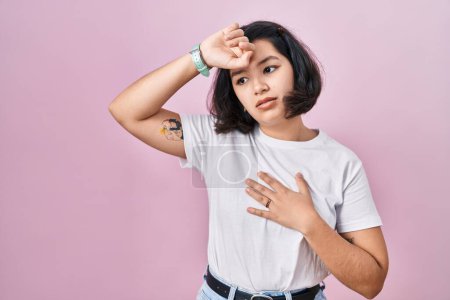 Photo for Young hispanic woman wearing casual white t shirt over pink background touching forehead for illness and fever, flu and cold, virus sick - Royalty Free Image