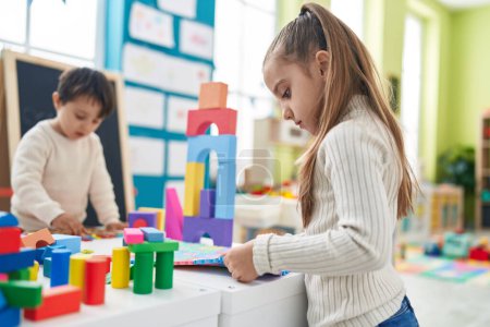 Photo for Adorable boy and girl playing with construction blocks and vocabulary puzzle at kindergarten - Royalty Free Image