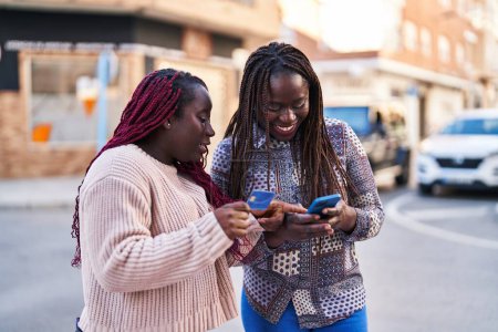 Foto de Amigas afroamericanas usando smartphone y tarjeta de crédito en la calle - Imagen libre de derechos