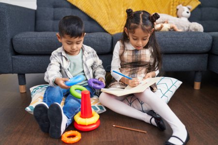 Téléchargez les photos : Adorable garçon et fille jouer avec cerceaux jeu dessin sur ordinateur portable à la maison - en image libre de droit