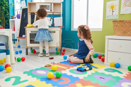 Photo for Adorable girls playing with play kitchen and car toy at kindergarten - Royalty Free Image