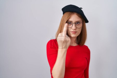 Foto de Young redhead woman standing wearing glasses and beret showing middle finger, impolite and rude fuck off expression - Imagen libre de derechos