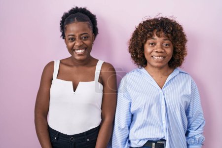 Téléchargez les photos : Deux femmes africaines debout sur fond rose clin d'oeil en regardant la caméra avec une expression sexy, gai et heureux visage. - en image libre de droit