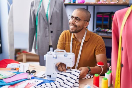 Téléchargez les photos : Young latin man tailor smiling confident using sewing machine at atelier - en image libre de droit