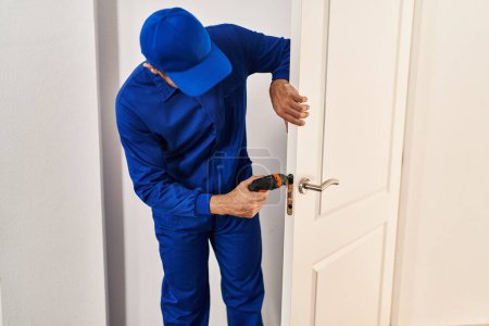 Téléchargez les photos : Jeune homme hispanique technicien réparer la porte à la maison - en image libre de droit