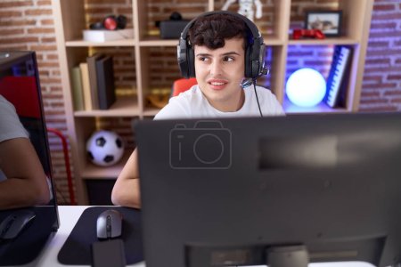 Téléchargez les photos : Non binaire homme streamer jouer à un jeu vidéo en utilisant l'ordinateur à la salle de jeu - en image libre de droit
