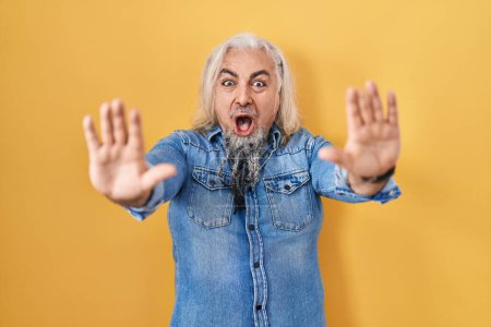 Photo for Middle age man with grey hair standing over yellow background doing stop gesture with hands palms, angry and frustration expression - Royalty Free Image