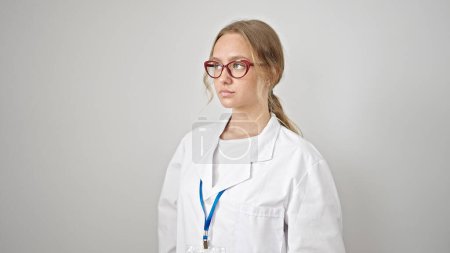 Photo for Young blonde woman doctor looking to the side with serious expression over isolated white background - Royalty Free Image
