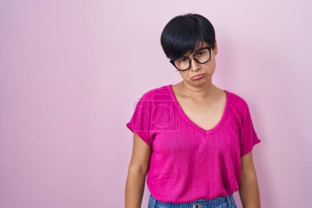 Téléchargez les photos : Jeune femme asiatique avec les cheveux courts debout sur fond rose déprimé et inquiet pour la détresse, pleurer en colère et peur. triste expression. - en image libre de droit