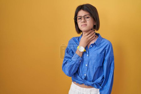 Photo for Young girl standing over yellow background touching painful neck, sore throat for flu, clod and infection - Royalty Free Image