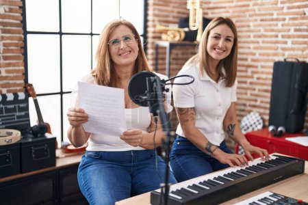 Foto de Madre e hija músicos cantando canciones tocando el piano en el estudio de música - Imagen libre de derechos
