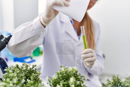 Foto de Mujer rubia joven vistiendo uniforme científico trabajando en el laboratorio - Imagen libre de derechos