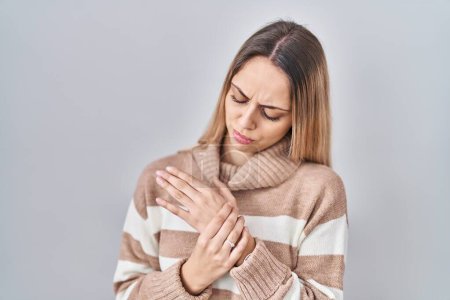 Foto de Mujer rubia joven que usa suéter de cuello alto sobre fondo aislado que sufre dolor en las manos y los dedos, inflamación de la artritis - Imagen libre de derechos
