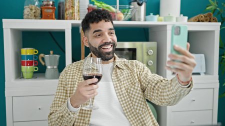 Foto de Joven hispano bebiendo copa de vino haciendo videollamada en el comedor - Imagen libre de derechos