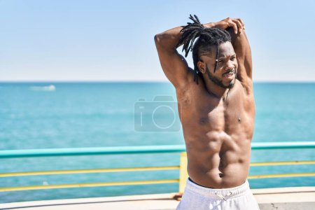 Photo for African american woman shirtless stretching arms at seaside - Royalty Free Image