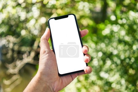 Téléchargez les photos : Homme tenant smartphone montrant écran blanc vierge au parc - en image libre de droit