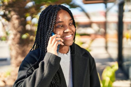 Téléchargez les photos : Femme afro-américaine souriant confiant parler sur le smartphone au parc - en image libre de droit
