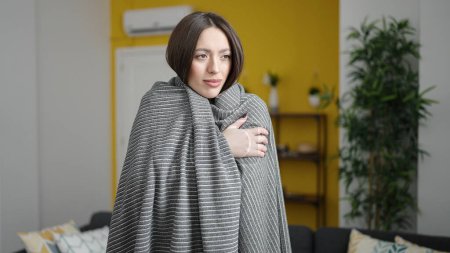 Foto de Joven hermosa mujer hispana cubriendo con manta para el frío en casa - Imagen libre de derechos