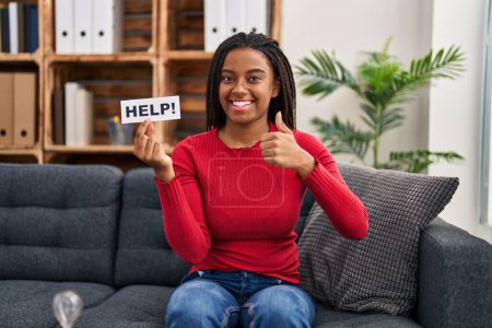 Photo for Young african american with braids doing therapy holding help banner smiling happy and positive, thumb up doing excellent and approval sign - Royalty Free Image