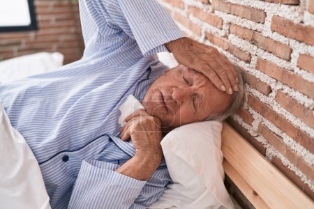 Foto de Enfermedad del hombre de pelo gris de mediana edad acostado en la cama en el dormitorio - Imagen libre de derechos