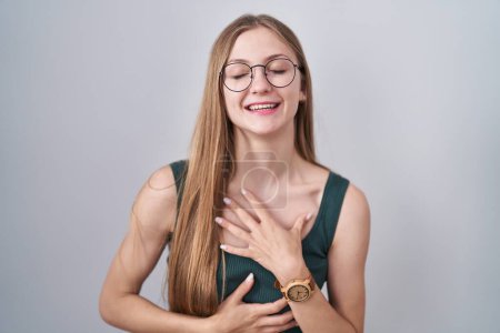 Téléchargez les photos : Jeune femme caucasienne debout sur fond blanc souriant et riant dur à haute voix parce que drôle blague folle avec les mains sur le corps. - en image libre de droit