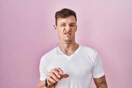 Photo for Caucasian man standing over pink background disgusted expression, displeased and fearful doing disgust face because aversion reaction. - Royalty Free Image