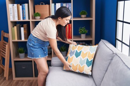 Photo for Young beautiful hispanic woman smiling confident organize sofa at home - Royalty Free Image