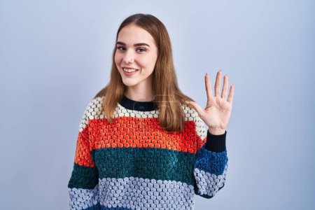Photo for Young hispanic girl standing over blue background showing and pointing up with fingers number five while smiling confident and happy. - Royalty Free Image