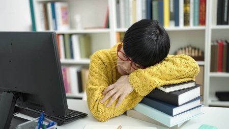 Photo for Young chinese woman student leaning on books sleeping at library university - Royalty Free Image