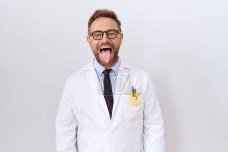 Photo for Middle age doctor man with beard wearing white coat sticking tongue out happy with funny expression. emotion concept. - Royalty Free Image