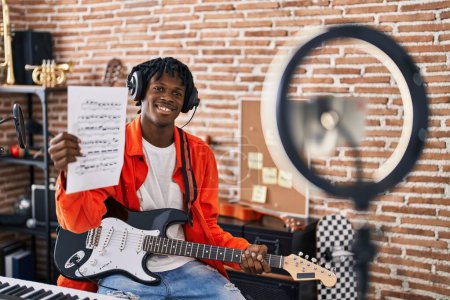 Foto de Africano americano hombre artista teniendo eléctrica guitarra en línea lección en estudio de música - Imagen libre de derechos